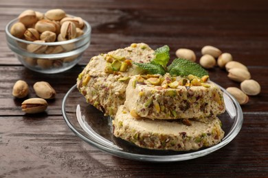 Photo of Tasty halva with pistachios and mint on wooden table, closeup