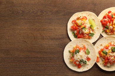 Photo of Delicious tacos with vegetables and lime on wooden table, top view. Space for text