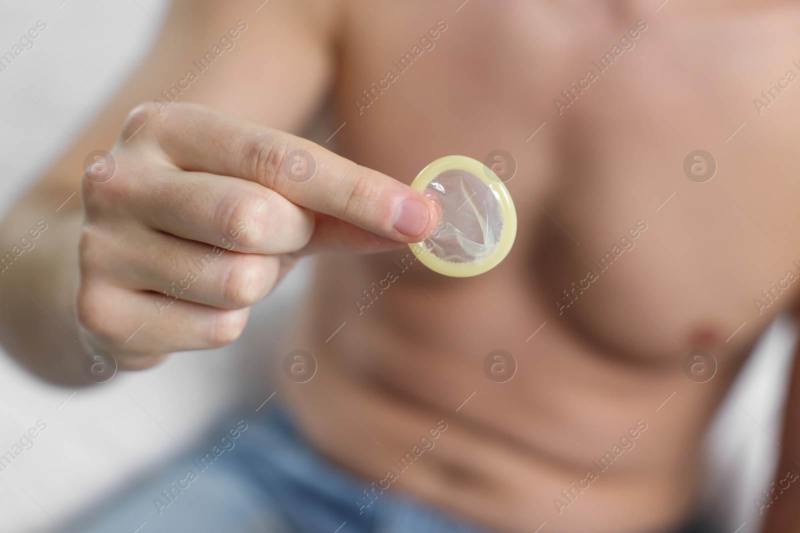 Photo of Closeup view of man showing condom on white background