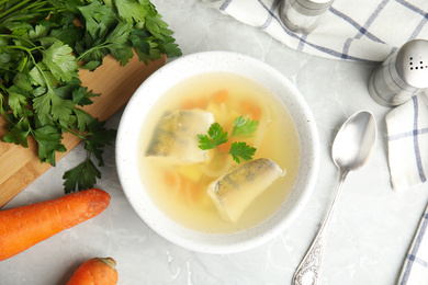 Photo of Delicious fish soup served on marble table, flat lay