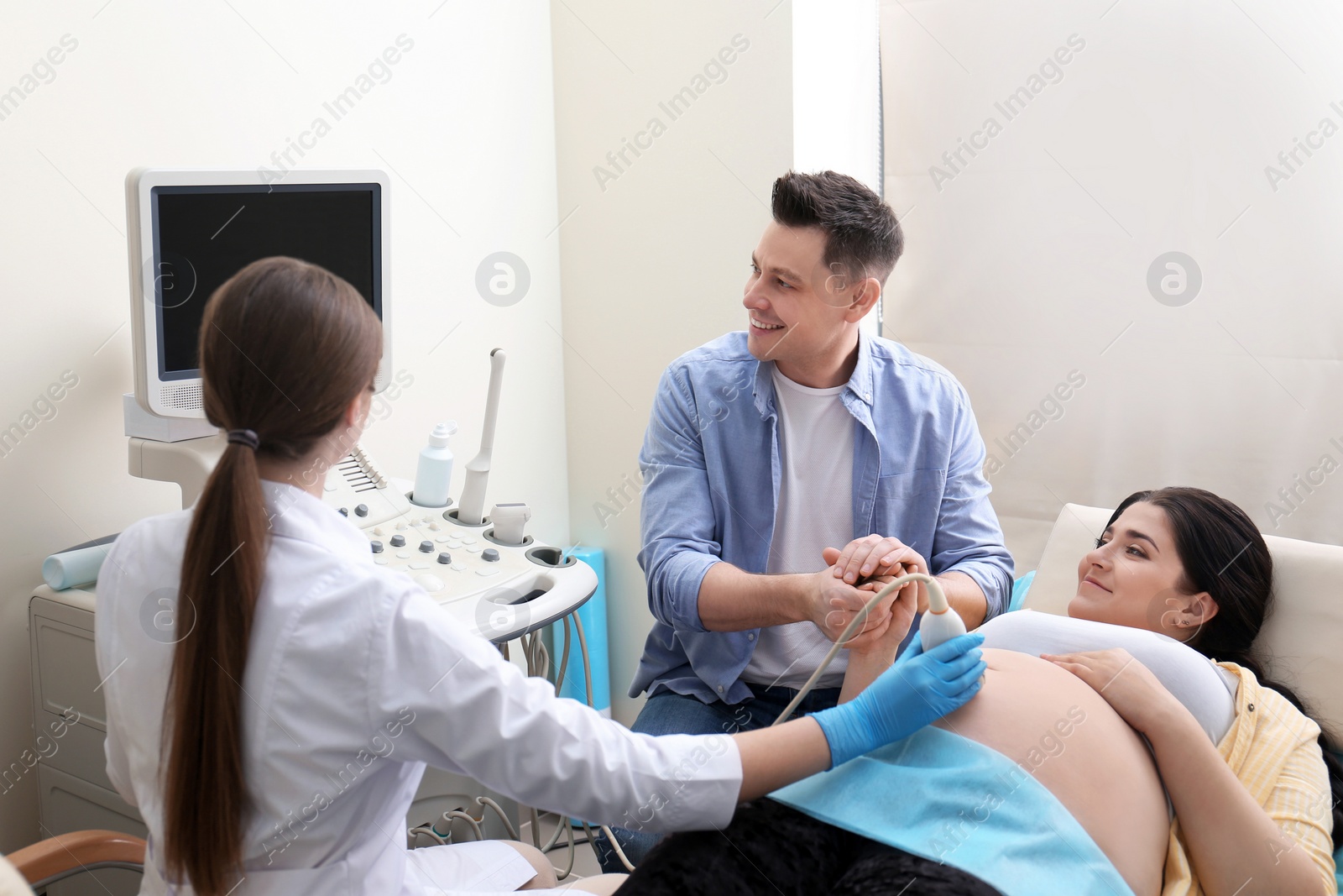 Photo of Man supporting his wife during ultrasound scan in clinic