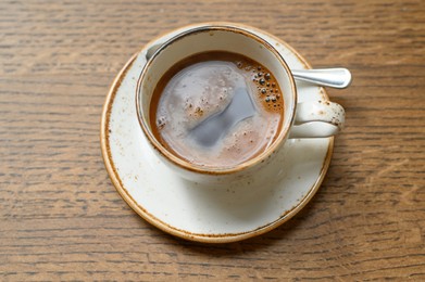 Cup of aromatic coffee on wooden table, above view