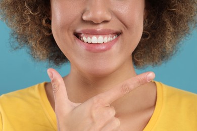 Photo of Woman showing her clean teeth and smiling on light blue background, closeup
