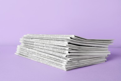 Stack of newspapers on light violet background. Journalist's work