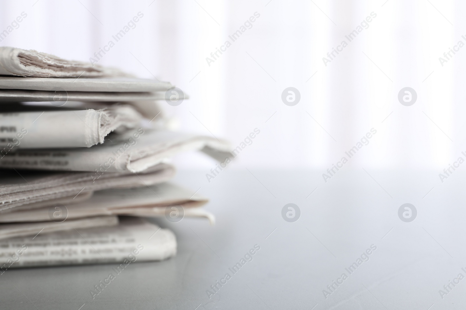 Photo of Pile of newspapers on grey table, space for text. Journalist's work