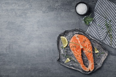 Photo of Fresh raw salmon steak with seasonings on gray background, top view