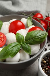 Photo of Delicious mozzarella balls in bowl, tomatoes and basil leaves on table, closeup