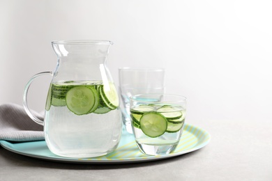 Photo of Glasses and jug of fresh cucumber water on tray. Space for text