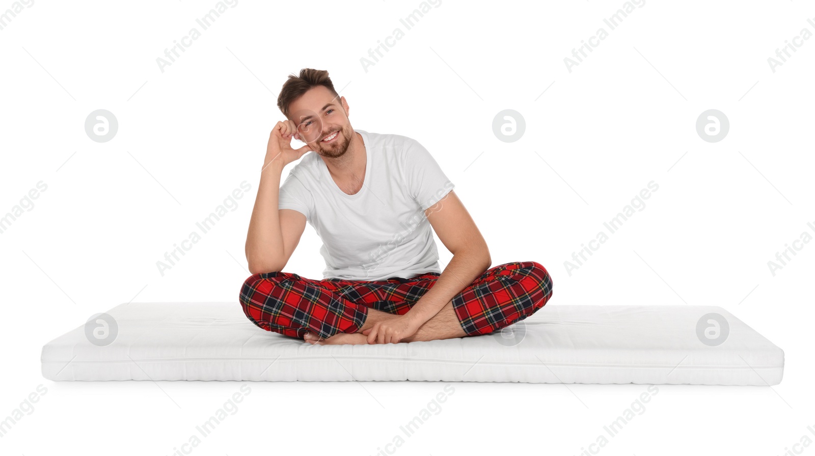 Photo of Smiling man sitting on soft mattress against white background