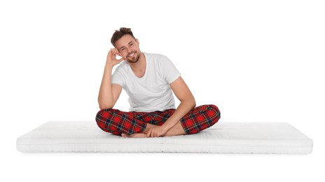 Photo of Smiling man sitting on soft mattress against white background