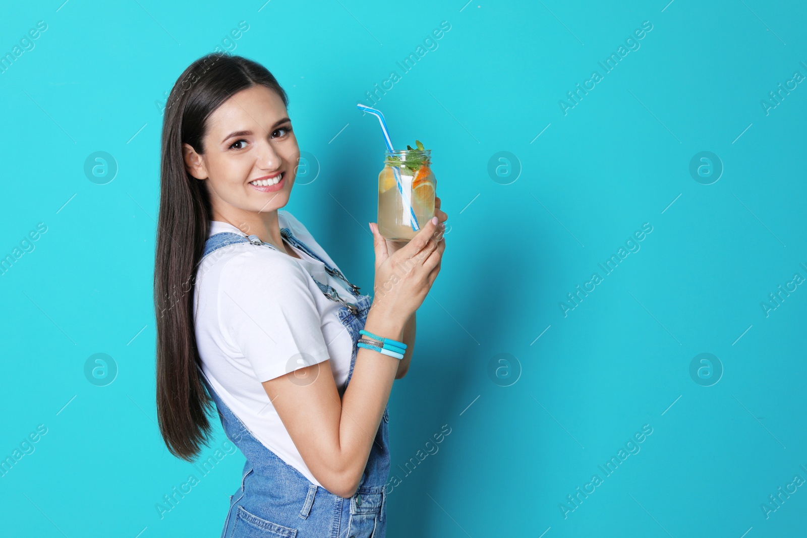 Photo of Young woman with mason jar of tasty lemonade on color background. Natural detox drink