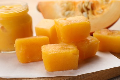 Photo of Frozen pumpkin puree cubes with ingredient on wooden board, closeup