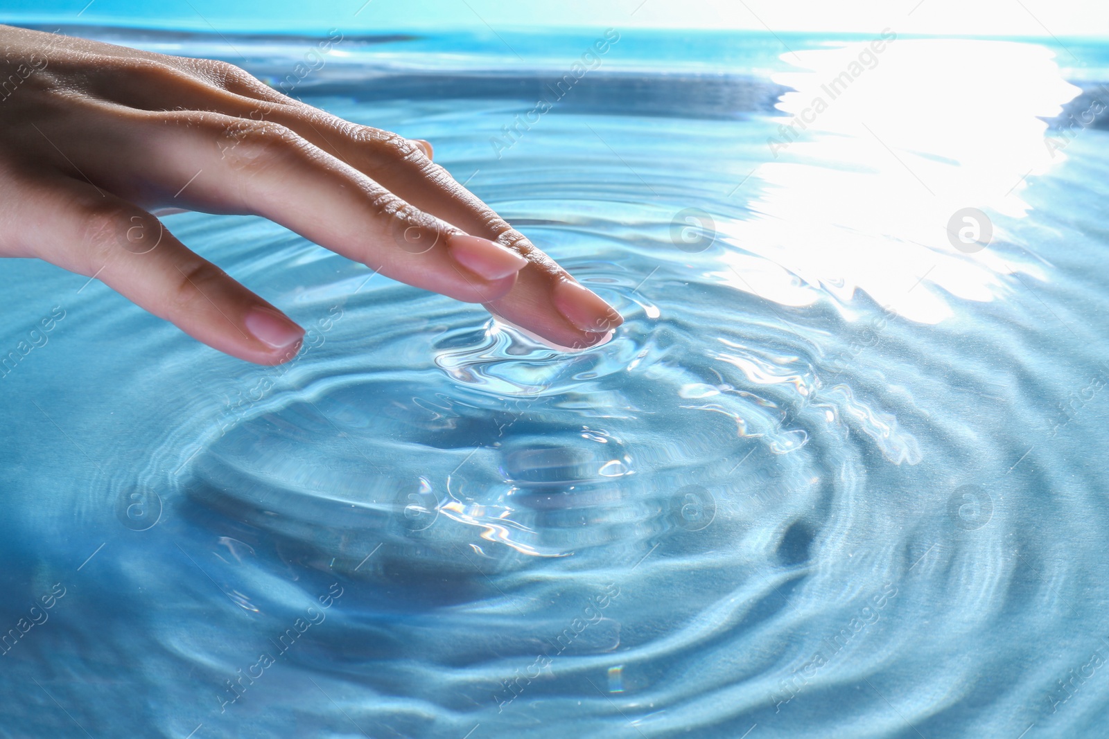 Photo of Woman touching clear water, closeup. Making ripples