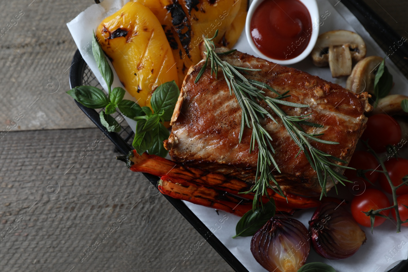 Photo of Delicious grilled meat and vegetables served with sauce on wooden table, top view