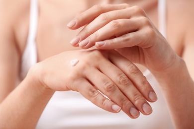 Photo of Young woman applying hand cream, closeup view