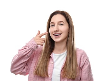 Portrait of smiling woman pointing at her dental braces on white background