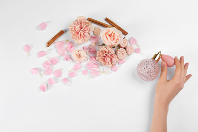 Photo of Woman with perfume. Fragrance composition, flowers and cinnamon on white background,  top view