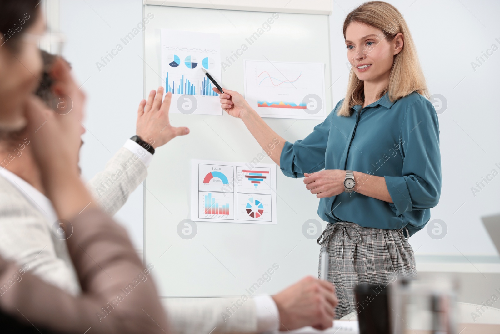 Photo of Businesswoman showing charts near flipchart on meeting in office