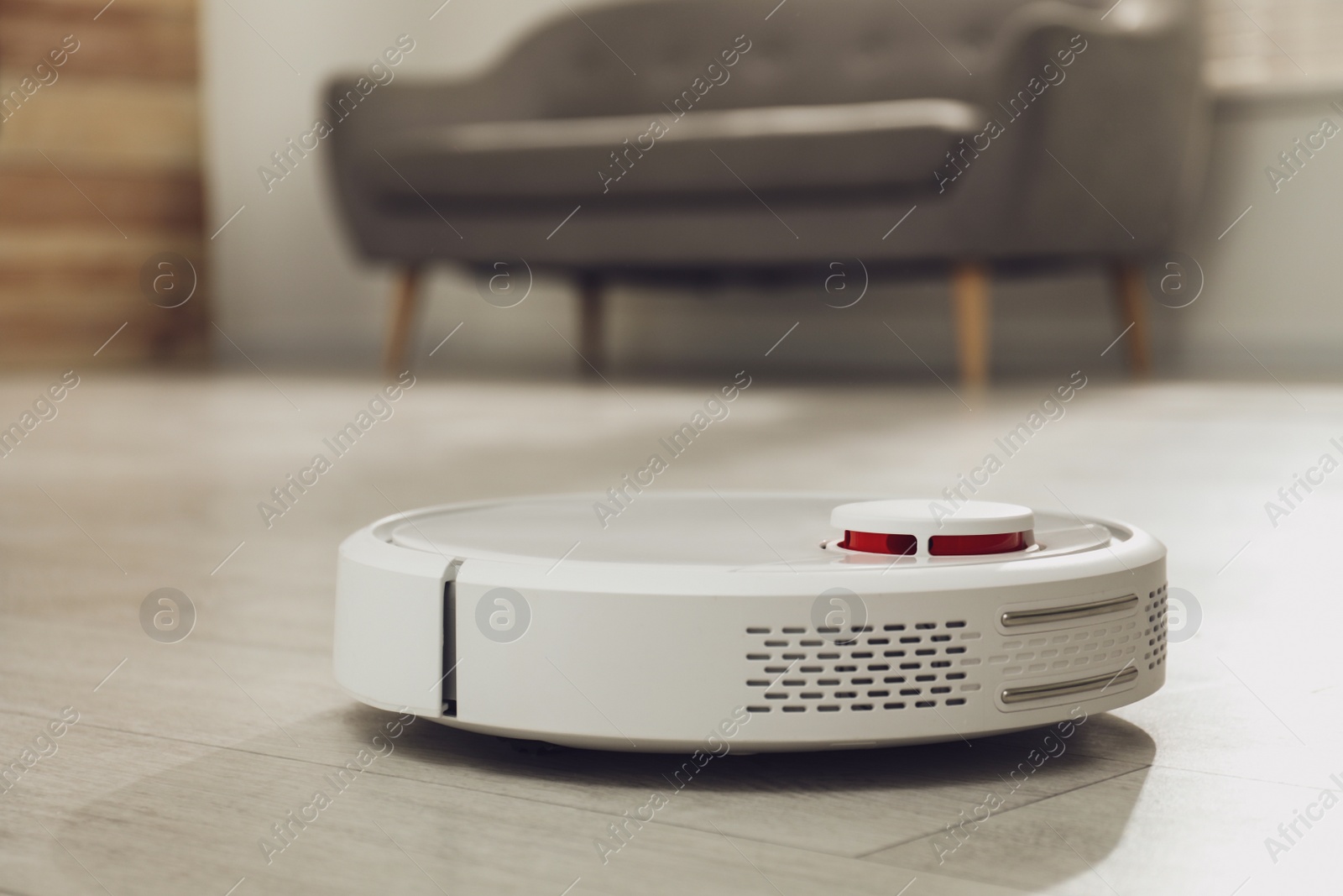 Photo of Modern robotic vacuum cleaner on floor in living room