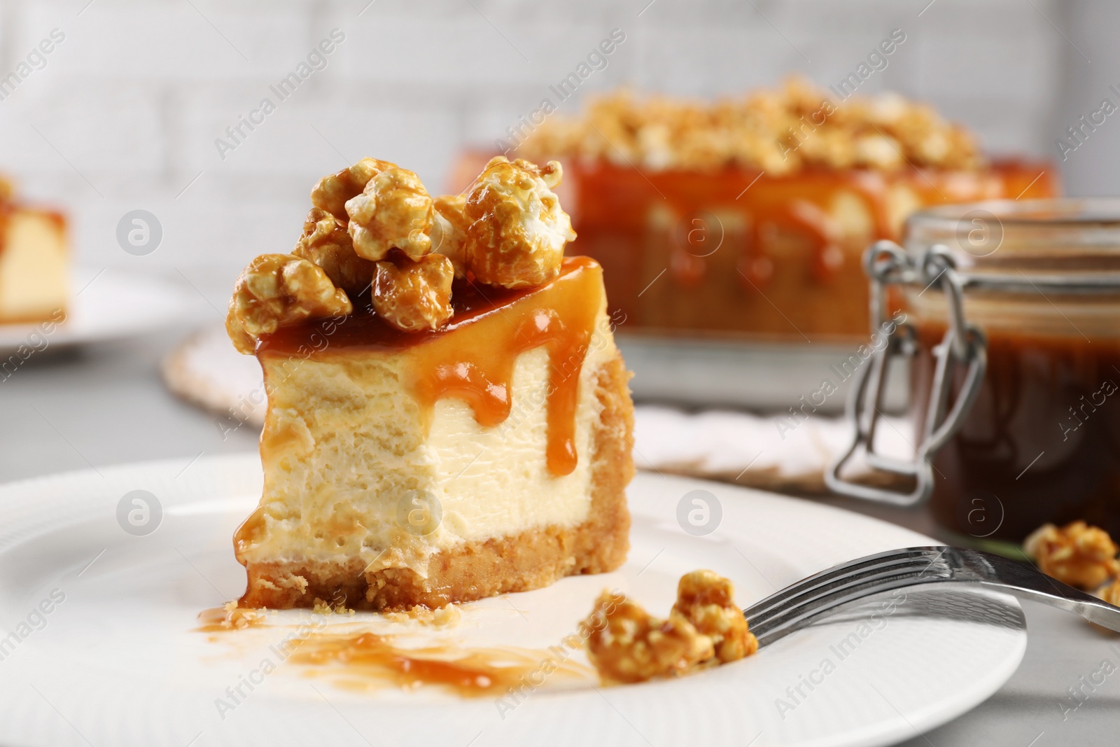 Photo of Piece of delicious caramel cheesecake with popcorn on table, closeup