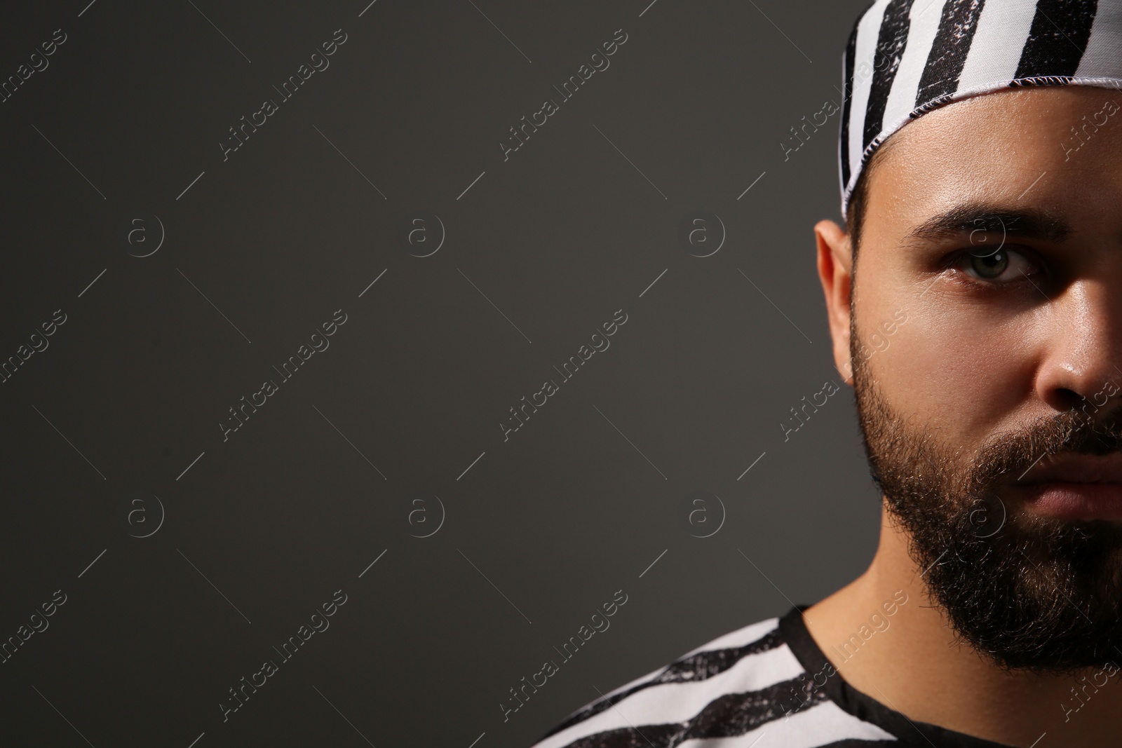 Photo of Prisoner in special uniform on dark grey background, closeup. Space for text
