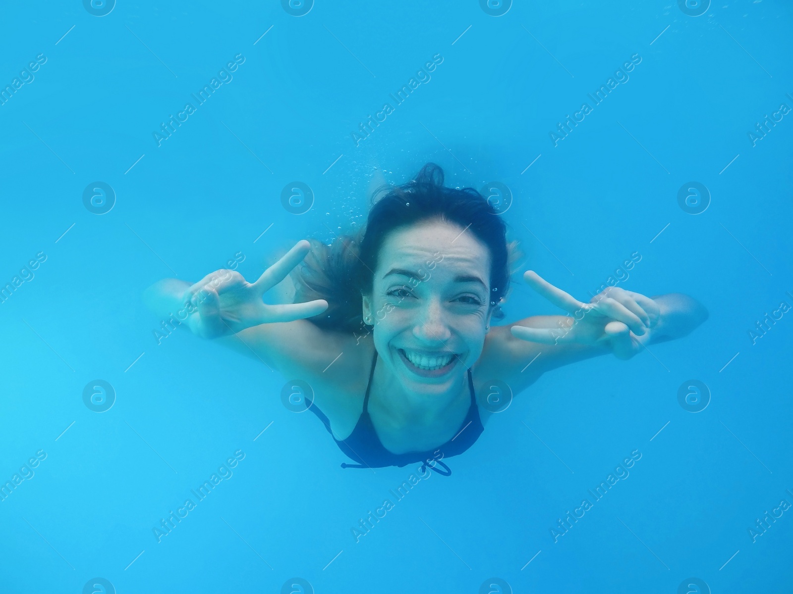 Photo of Beautiful young woman swimming in pool, underwater view