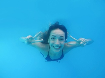 Beautiful young woman swimming in pool, underwater view