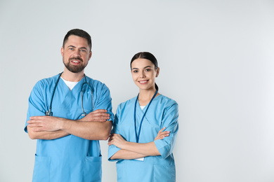 Photo of Mature doctor and young nurse against light background