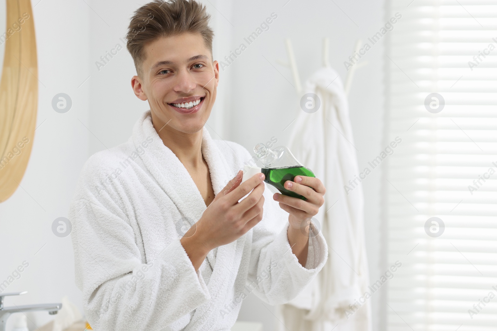 Photo of Young man with mouthwash in bathroom. Oral hygiene