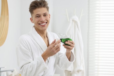 Photo of Young man with mouthwash in bathroom. Oral hygiene