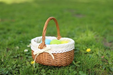 Easter celebration. Painted eggs in wicker basket on green grass