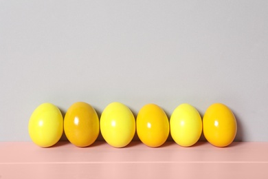Photo of Easter eggs on pink wooden table against light grey background, space for text