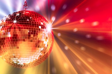 Image of Shiny bright disco ball under color lights, space for text