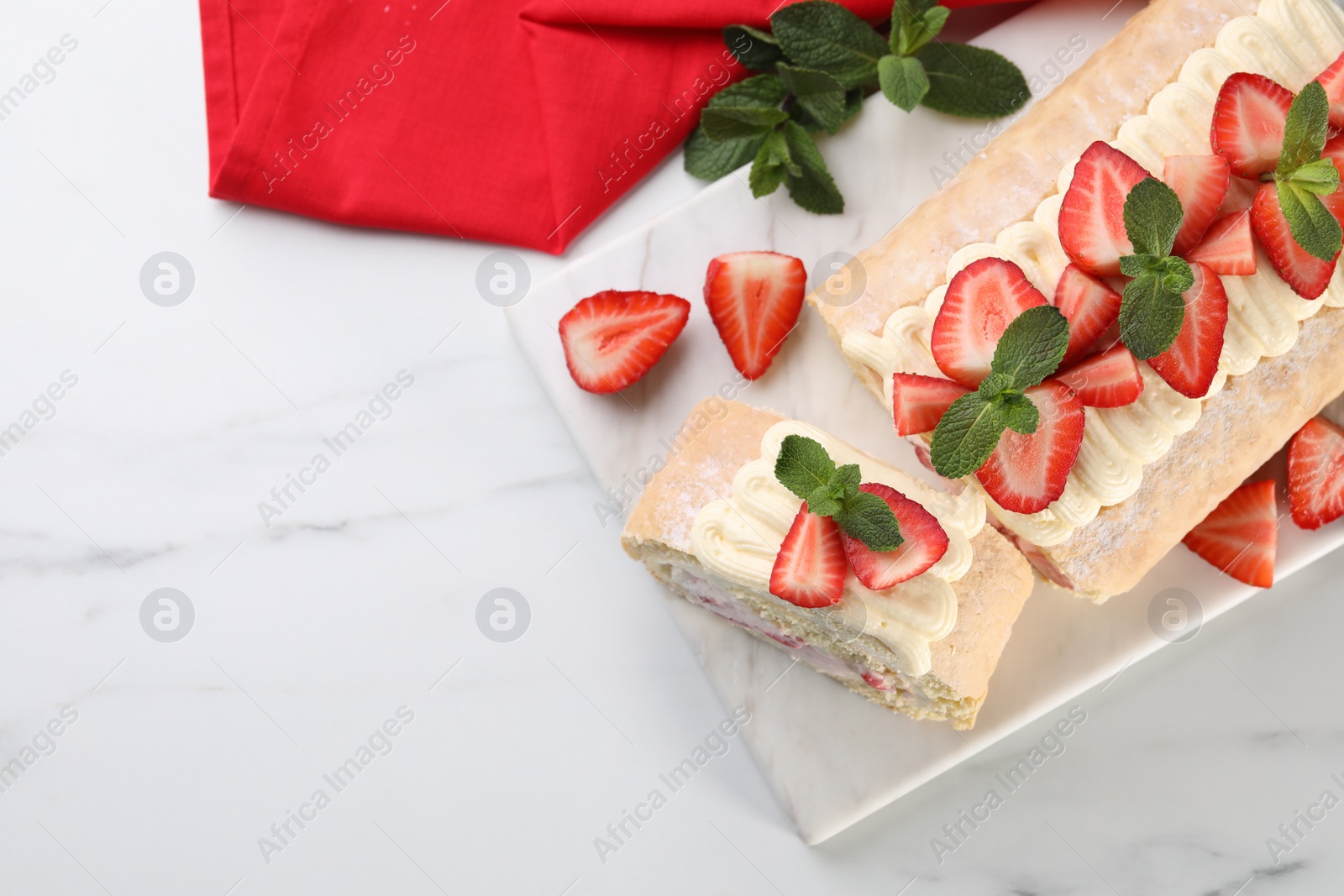 Photo of Delicious cake roll with strawberries and cream on white marble table, top view. Space for text