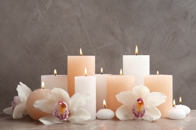 Beautiful composition with candles and flowers on table against grey background