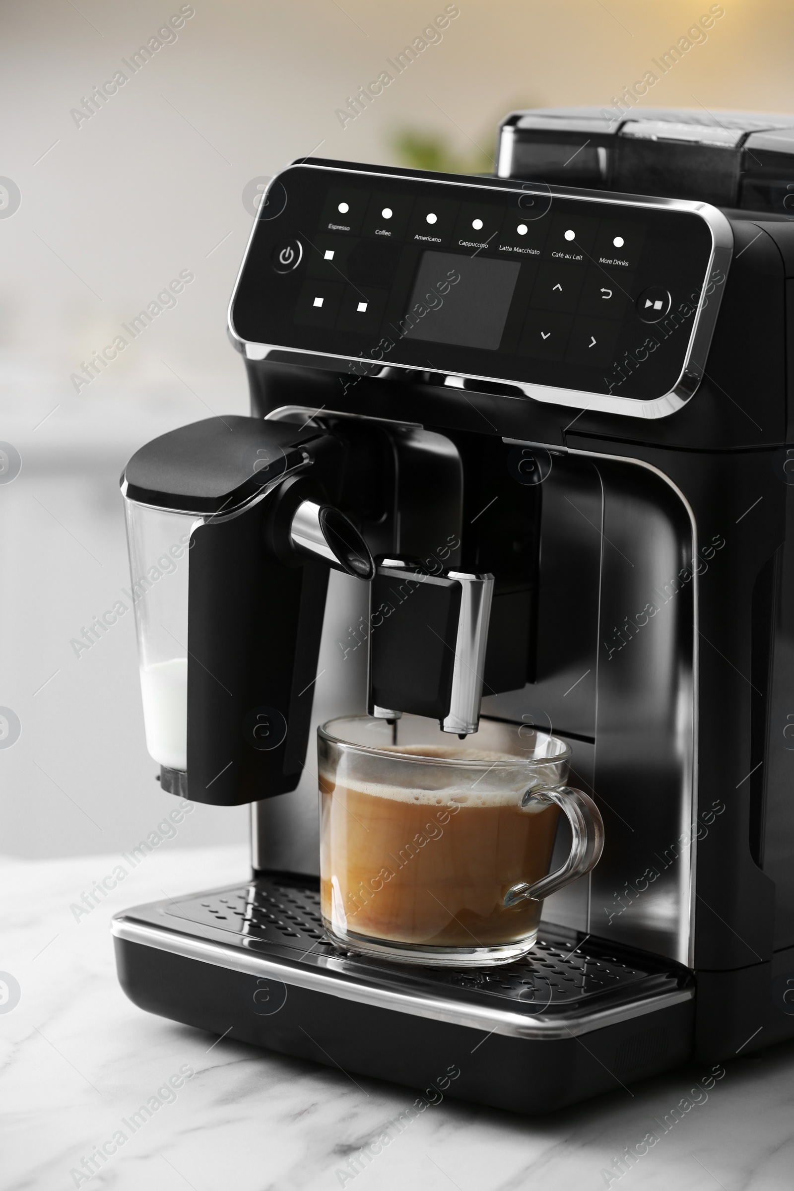 Photo of Modern espresso machine and glass cup of coffee with milk on white marble countertop in kitchen