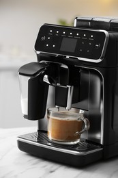 Photo of Modern espresso machine and glass cup of coffee with milk on white marble countertop in kitchen