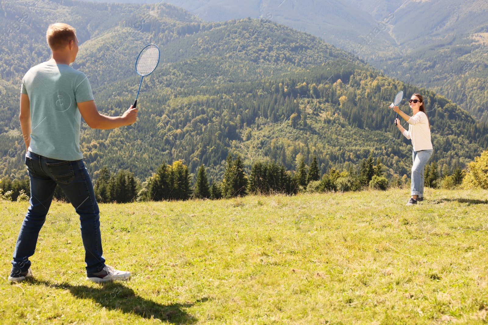 Photo of Couple playing badminton in mountains on sunny day