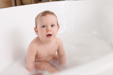 Cute little baby bathing in tub at home