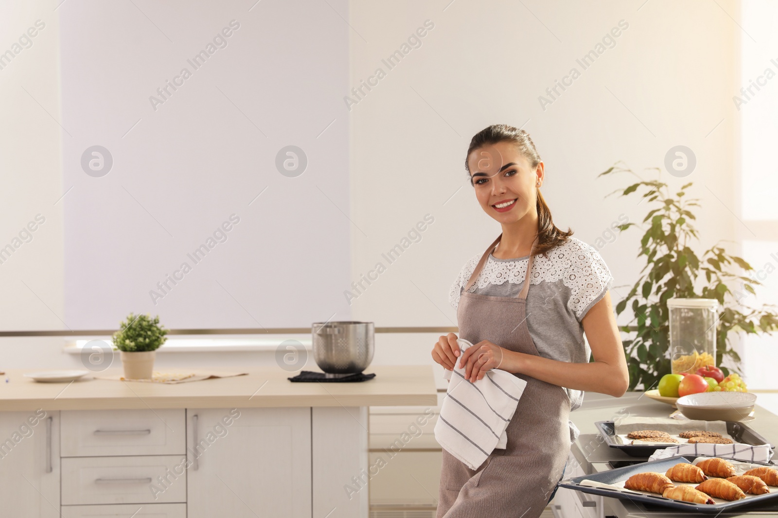 Photo of Young woman with homemade oven baked pastry in kitchen, space for text