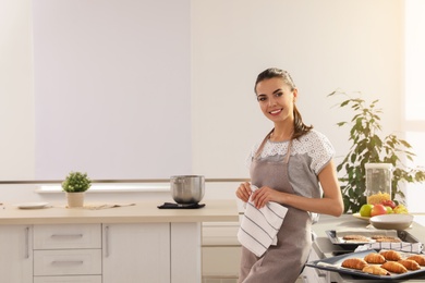 Photo of Young woman with homemade oven baked pastry in kitchen, space for text