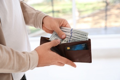 Photo of Man holding wallet with money on blurred background, closeup