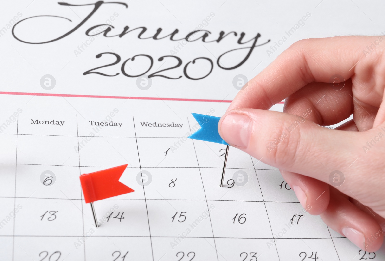 Photo of Woman marking date in calendar with drawing pin, closeup