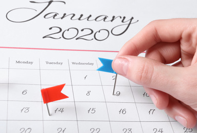 Photo of Woman marking date in calendar with drawing pin, closeup