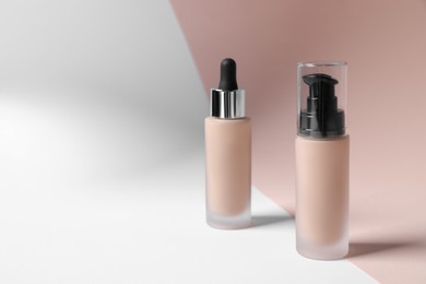 Bottles of skin foundation on color background, space for text. Makeup product
