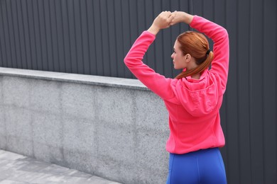 Woman in gym clothes doing exercises on street, back view. Space for text