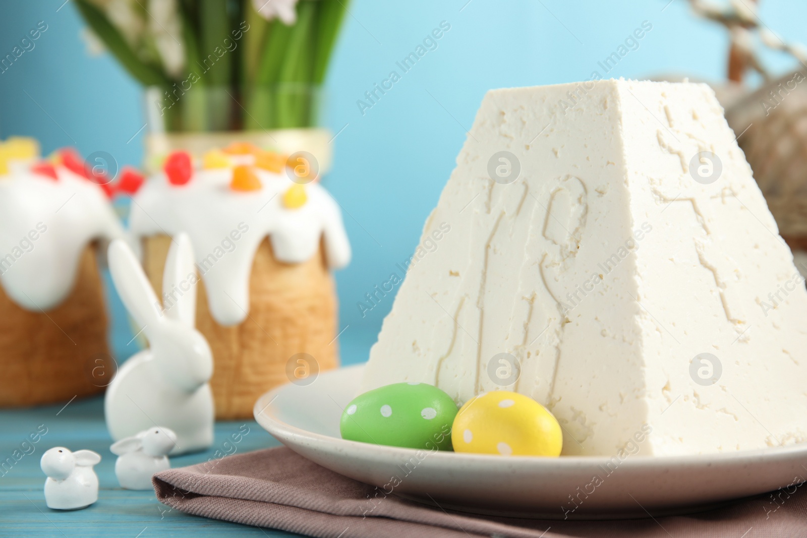 Photo of Traditional cottage cheese Easter paskha on light blue wooden table, closeup. Space for text