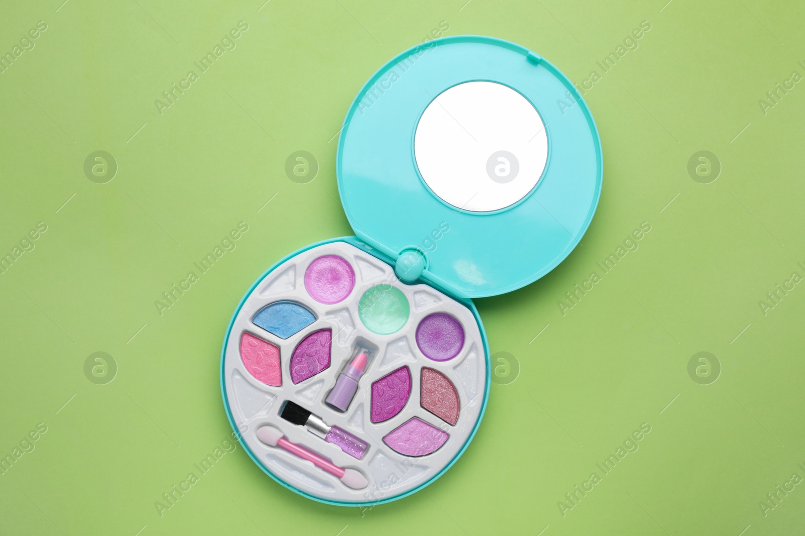 Photo of Decorative cosmetics for kids. Eye shadow palette with lipstick on light green background, top view
