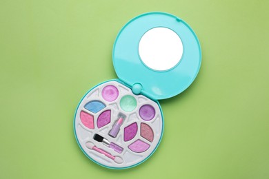 Photo of Decorative cosmetics for kids. Eye shadow palette with lipstick on light green background, top view