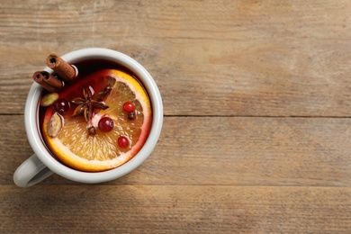 Cup of tasty mulled wine on wooden table, top view. Space for text